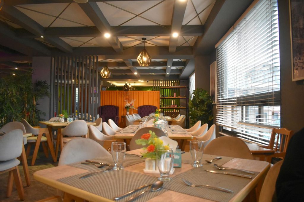 A warm and stylish restaurant interior featuring elegant wooden tables and cozy seating under ambient lighting.